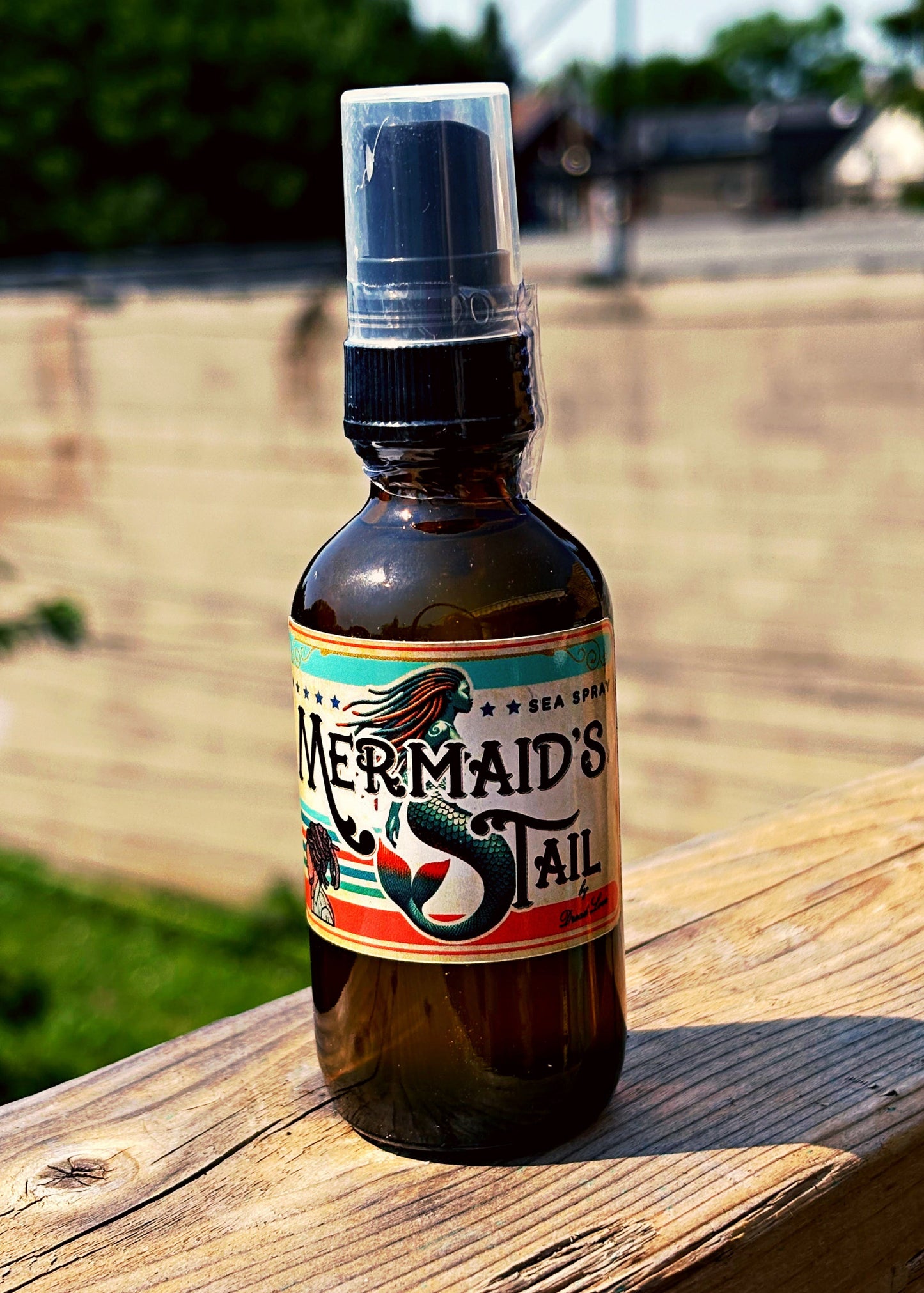 Mermaid's Tail bottle spray on a wooden surface with a blurred outdoor background