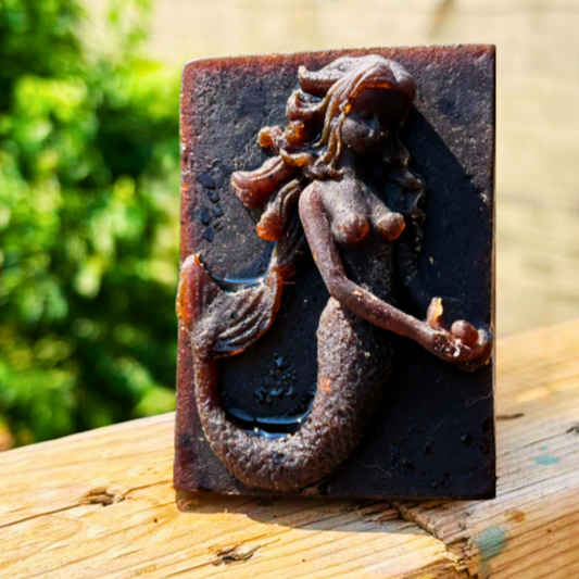 African Black Soap Decorative mermaid shampoo Bar on a wooden surface with a blurred natural background