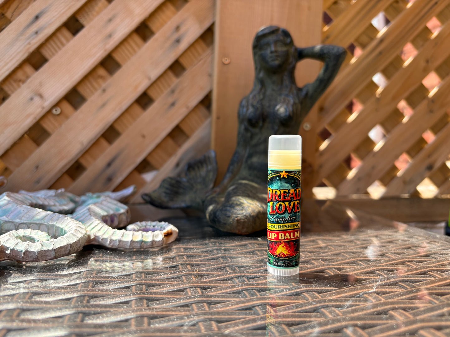 Single Dread Love Toasted Marshmallow Nourishing Lip Balm tube on an outdoor table 