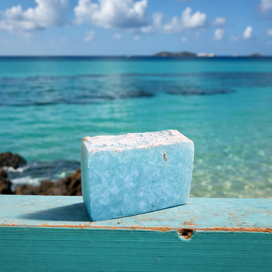 Blue shampoo bar of soap on a wooden surface with a scenic ocean view in the background