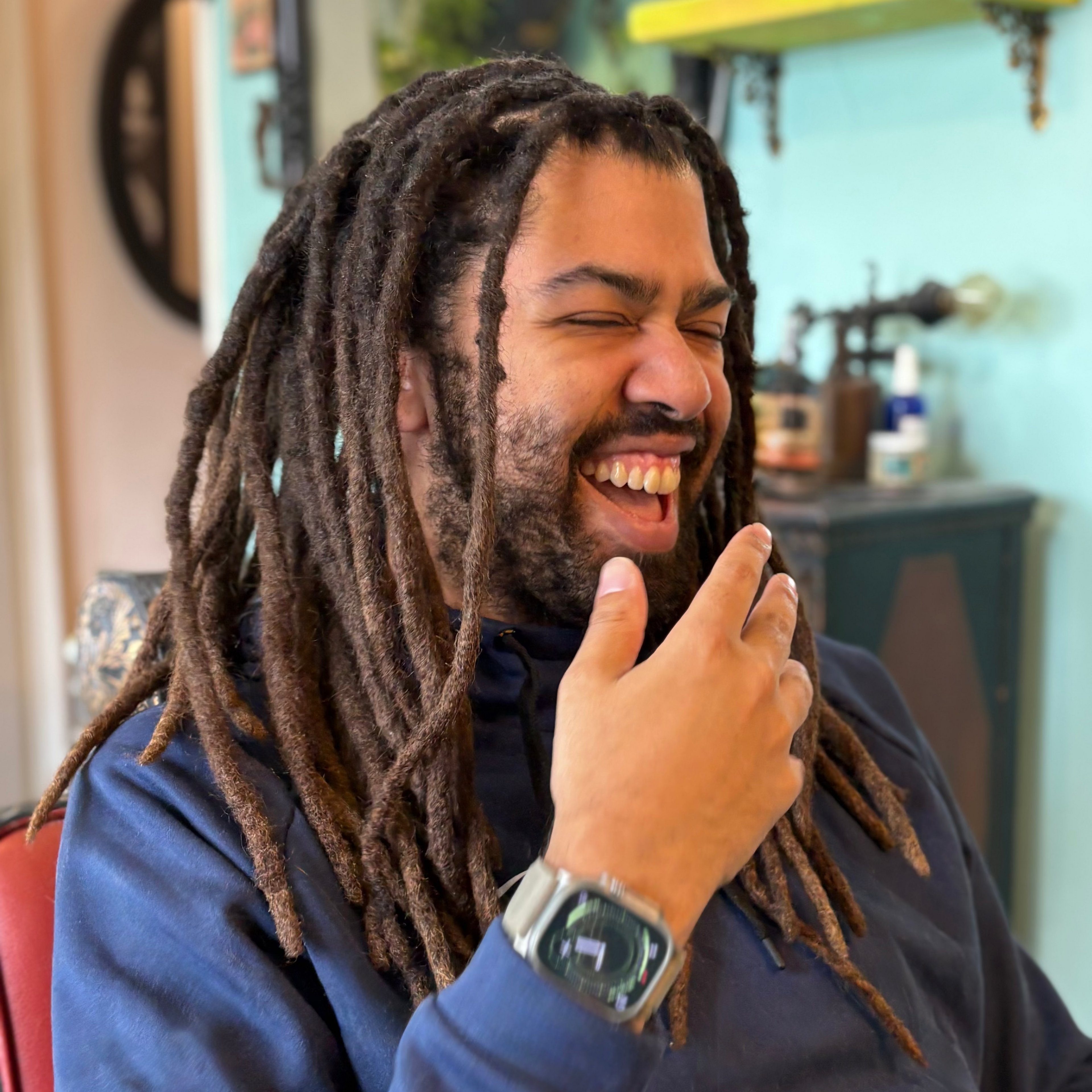 Man with dreadlocks laughing in a barbershop setting Dread Love Tooronto