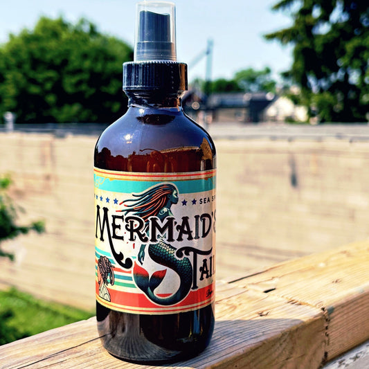 Bottle of 'Mermaid Tail' spray on a wooden surface with a natural background